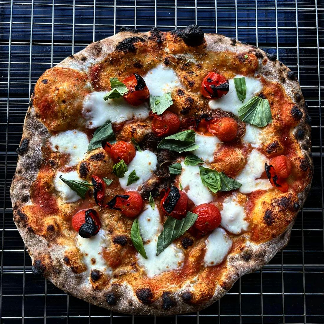 Wood-fired pizza with tomatoes, mozzarella and basil